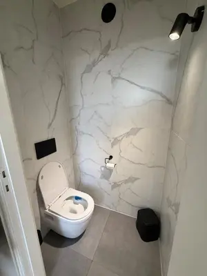 a bathroom with a toilet and a marble wall at TML 500m - Luxury Penthouse with 2 Balconies in Boom