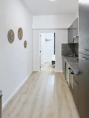 a kitchen with white walls and a wooden floor at Élégant appartement une chambre in Brussels