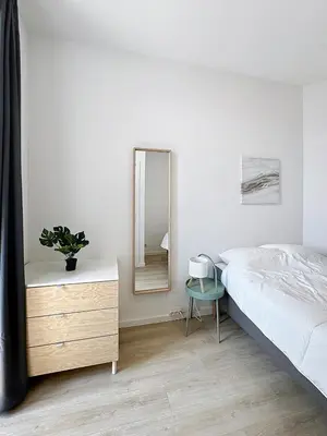 a bedroom with a bed and a dresser and a mirror at Élégant appartement une chambre in Brussels