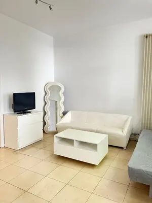a living room with a white couch and a tv at The Heart of Petit Sablon in Brussels
