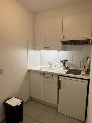 a small kitchen with white cabinets and a sink at The Heart of Petit Sablon in Brussels