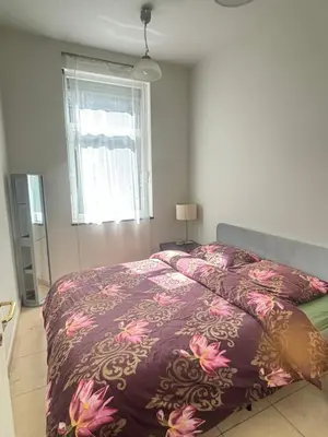 a bedroom with a bed with a purple comforter and a window at The Heart of Petit Sablon in Brussels