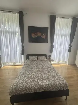 a bedroom with a bed and two large windows at Studio Lilia in Brussels