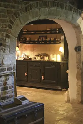 a kitchen with black cabinets and a stone wall at Gastenlogies Blauwe Schaap in Ranst
