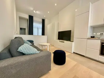 a living room with a gray couch and a kitchen at Chapeliers in Brussels