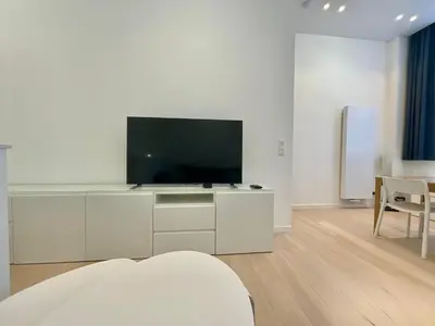 a white living room with a flat screen tv at Chapeliers in Brussels