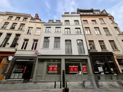 a tall white building with windows on a street at Chapeliers in Brussels