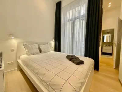 a large white bed in a room with a window at Chapeliers in Brussels