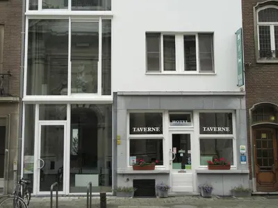 a large white building with glass windows on a street at Hotel Muske Pitter in Mechelen
