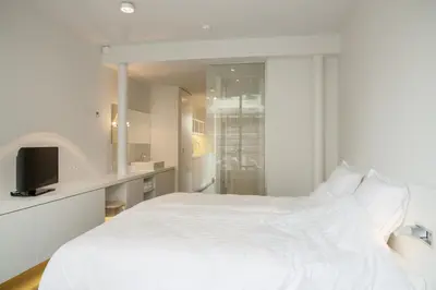 a white bedroom with a white bed and a tv at Hotel Muske Pitter in Mechelen
