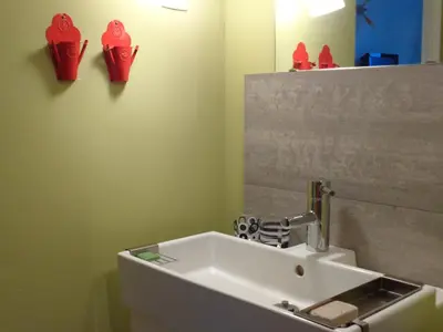 a bathroom with a sink and red boots on the wall at B&B La Chambre du Zodiaque in Brussels