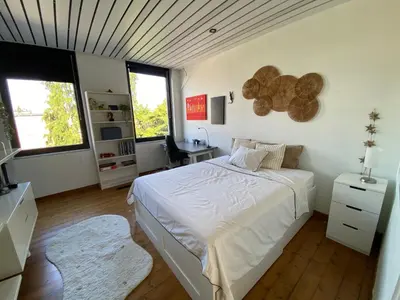 a bedroom with a bed and a desk and windows at Huis krekelhof in Antwerp