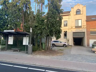 a bus stop with a car parked in front of a building at Huis krekelhof in Antwerp