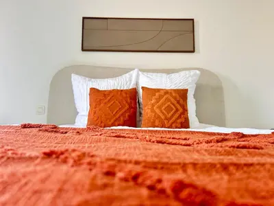 a bed with an orange blanket and two pillows at Apartment for 6 people - near Brussels & Airport in Wezembeek-Oppem