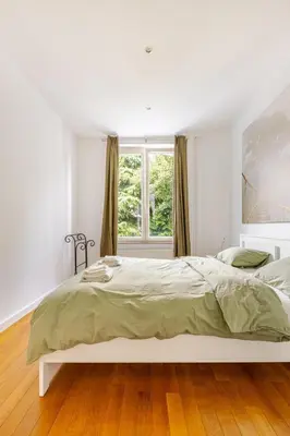 a white bedroom with a large bed and a window at Maison du Cinquantenaire - The Residential in Brussels
