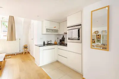 a kitchen with white cabinets and a counter top at Maison du Cinquantenaire - The Jubilee Loft in Brussels