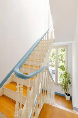 a white staircase with a blue rail at Maison du Cinquantenaire - The Jubilee Loft in Brussels
