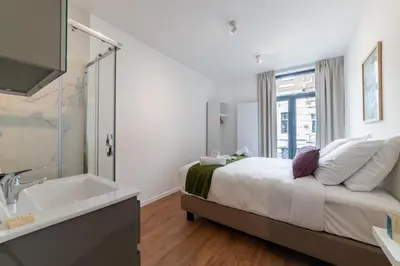 a bedroom with a bed and a sink and a tub at Chez Lilou et Babette 4 appartements 2 chambres in Brussels