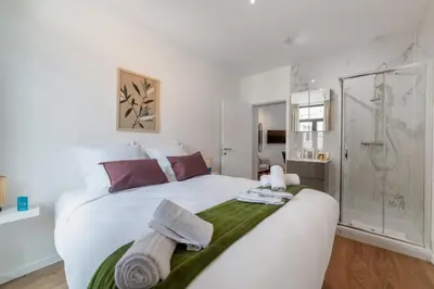 a bedroom with a large white bed and a shower at Chez Lilou et Babette 4 appartements 2 chambres in Brussels