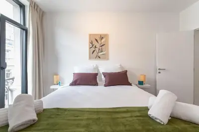 a white bedroom with a large bed with red pillows at Chez Lilou et Babette 4 appartements 2 chambres in Brussels