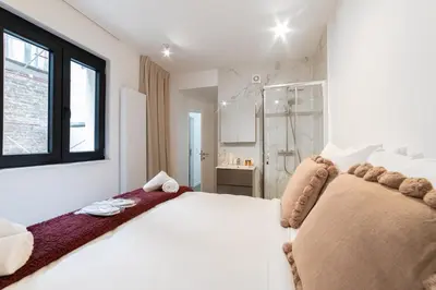 a white bedroom with a large bed and a shower at Chez Lilou et Babette 4 appartements 2 chambres in Brussels