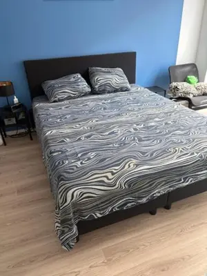 a bed with a black and white comforter in a bedroom at Radja in Boom
