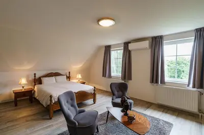 a bedroom with a bed and two chairs and a table at Guesthouse De Meelberg in Beringen