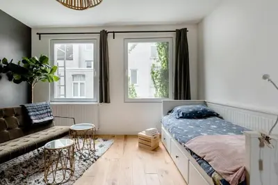 a bedroom with a bed and a couch and two windows at Charming Private Studio - Nearby Antwerp Central Station in Antwerp