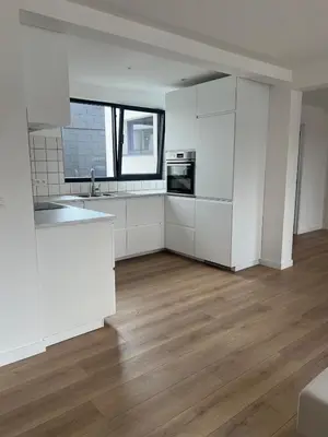 an empty kitchen with white cabinets and a wooden floor at Libre in Temse