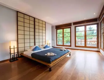 a bedroom with a large bed in a room with windows at Havre de Paix à Bruxelles avec piscine et sauna in Brussels