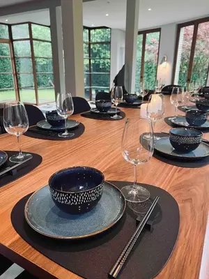 a long wooden table with glasses and plates on it at Havre de Paix à Bruxelles avec piscine et sauna in Brussels