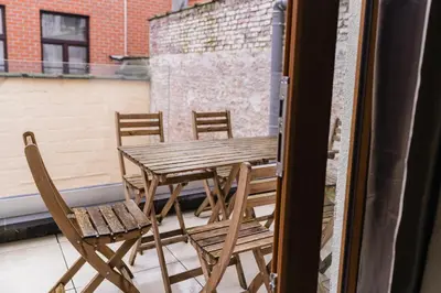 a wooden table and chairs on a balcony at Elegant 3BR & 1LR Waterfront Retreat in Ghent in Ghent