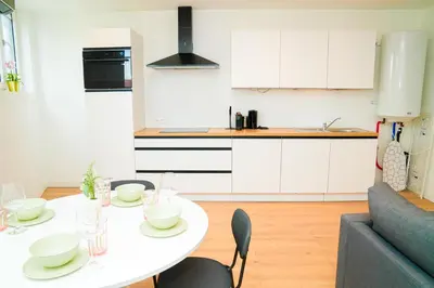 a white kitchen with a white table and chairs at Modern 1BR & 1LR Apartment, 10 min Walk to City Center in Ghent