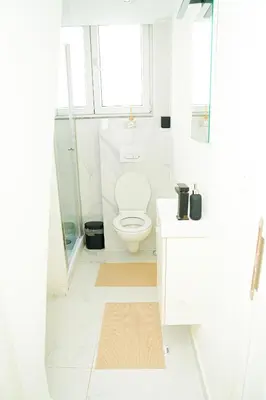 a white bathroom with a toilet and a window at Modern 1BR & 1LR Apartment, 10 min Walk to City Center in Ghent