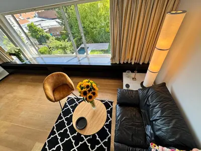 a living room with a couch and a table with a sunflower at Villa 'L' in Brussels