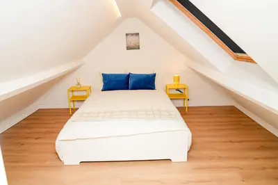 a white bed with blue pillows in a attic at Chic & Modern 1BR & 1LR Apt, 12 Min Walk to Rabot in Ghent