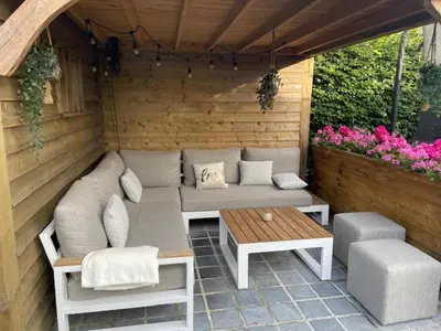 a patio with a couch and a table and flowers at Casa Duffla in Duffel