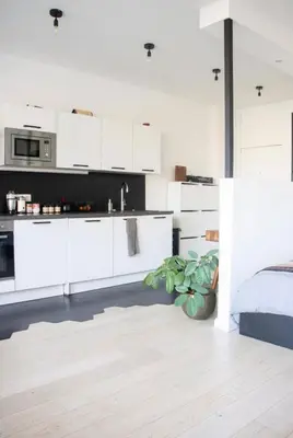 a white kitchen with white cabinets and a bed at Cozy apartment - Super central in Brussels