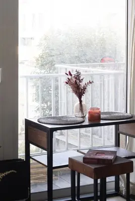 a table with a vase of flowers on it next to a window at Cozy apartment - Super central in Brussels