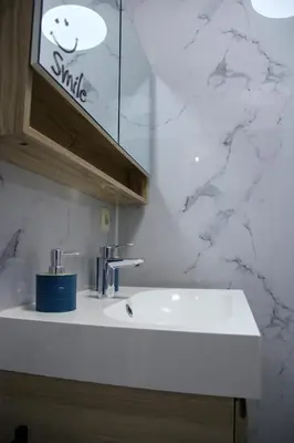 a white sink in a bathroom with marble walls at Aurelia in Zemst