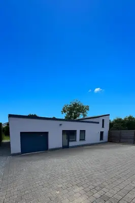 a white building with two garage doors in a parking lot at Aurelia in Zemst