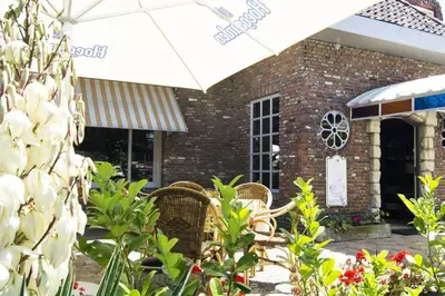 a brick building with two chairs and an umbrella at Hotel Pacific in Weelde
