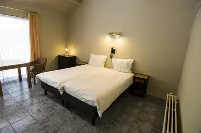 a bedroom with a large bed with white sheets and a table at Hotel Pacific in Weelde