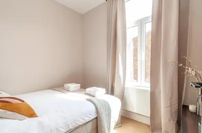 a white bedroom with two beds and a window at Stylish Apartment in 't Zuid in Antwerp