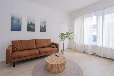 a living room with a brown couch and a table at Chic Antwerp Stay 3BR Comfort in Antwerp