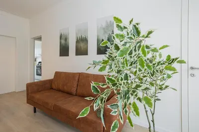 a living room with a brown couch and a plant at Chic Antwerp Stay 3BR Comfort in Antwerp