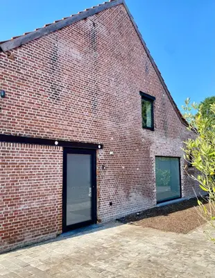 a brick building with two garage doors on it at Hoeve DeKleinheide - De Hoeve in Dessel