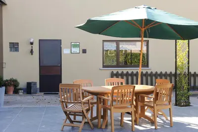 a wooden table with chairs and an umbrella at Hof Ter Hagen in Lokeren
