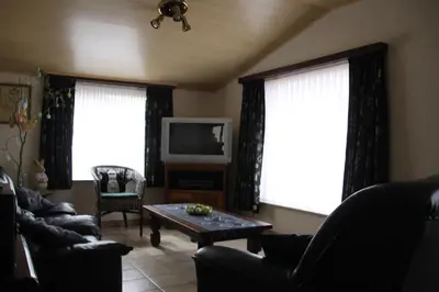 a living room with a couch and a table and two windows at Hof Ter Hagen in Lokeren