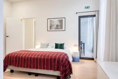 a white bedroom with a bed with a red blanket at The Ghentian Suites by Domani Hotels in Ghent